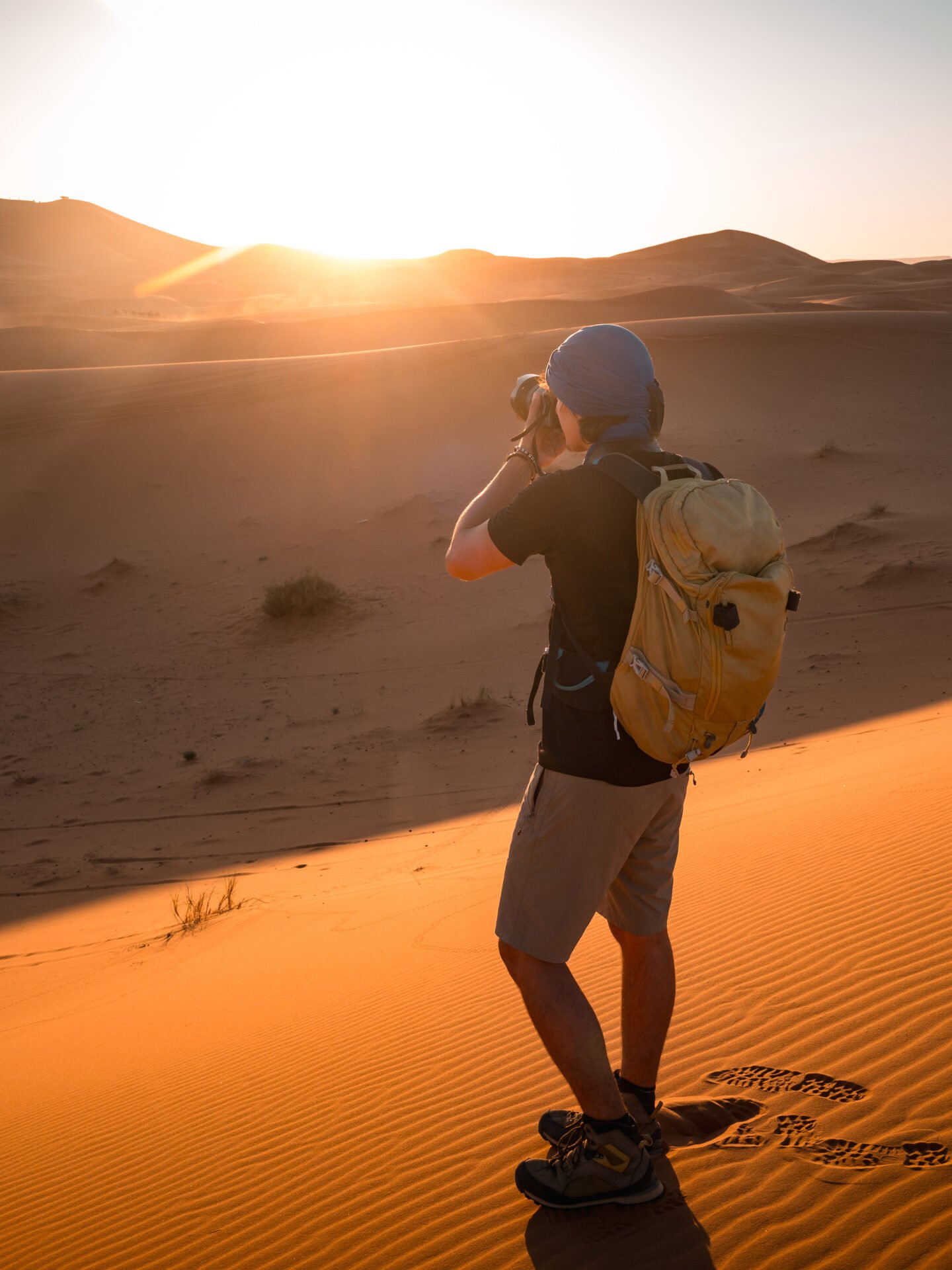 Photographer taking pictures of sunrise in merzouga desert, morocco